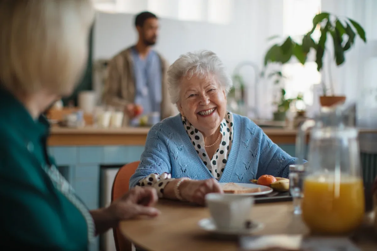 Elderly woman enjoying breakfast in a senior care setting, reflecting how to get someone with dementia to eat with calm support and familiar routines.